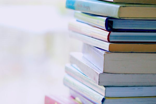 A tall stack of colorful hardcover books on a table indoors, perfect for library-themed concepts.