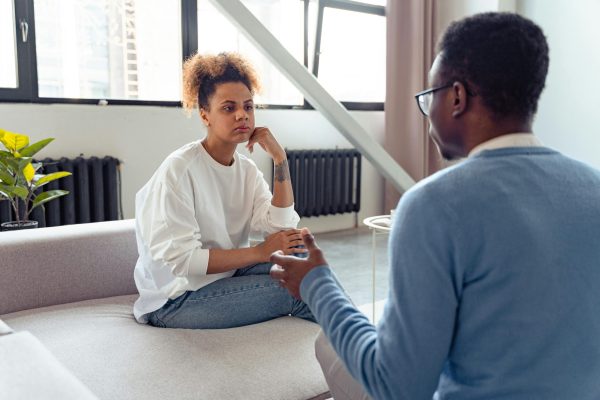 Two individuals engaged in a thoughtful therapy session indoors.